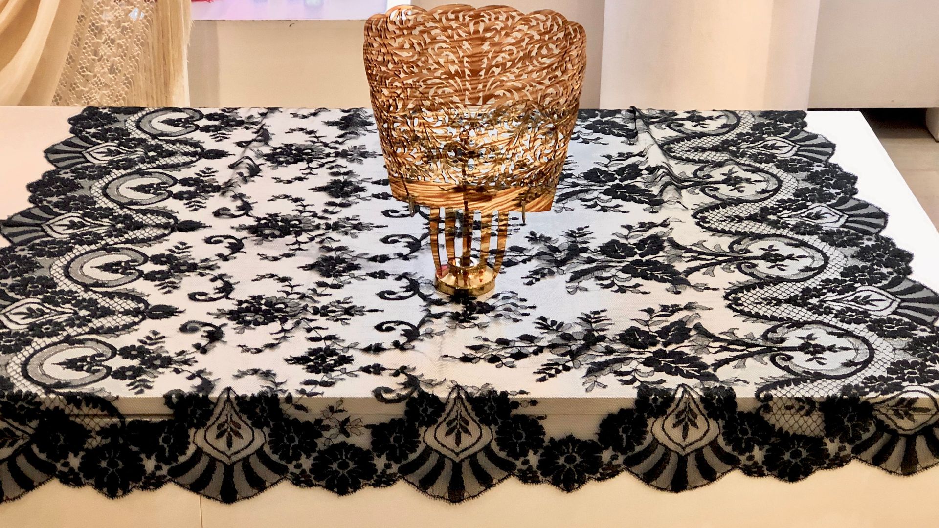 Un mantel de encaje blanco y negro con un jarrón dorado encima.