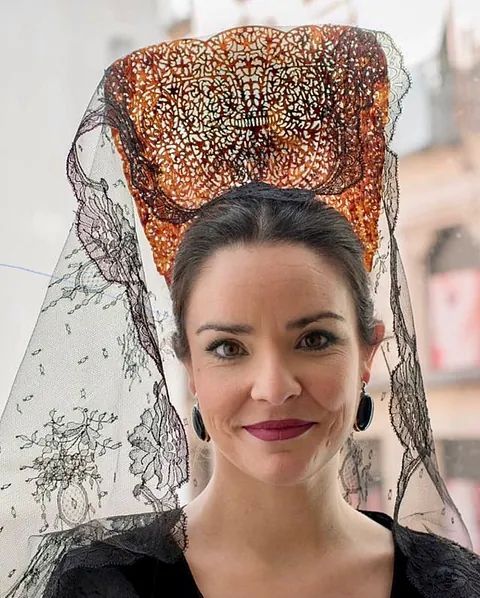 Una mujer con velo y pendientes mira a la cámara.