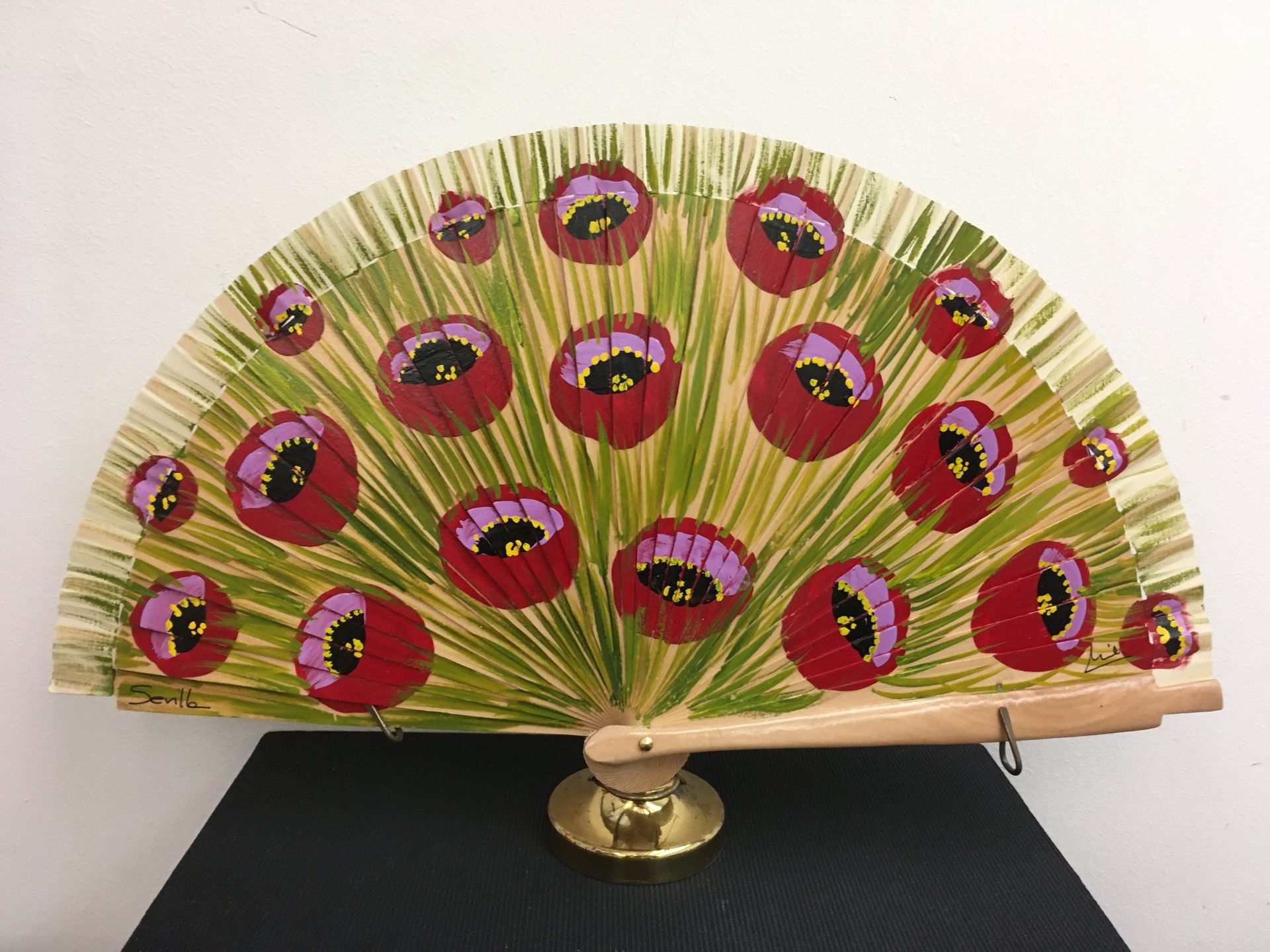 Un abanico con flores rojas y moradas pintadas.