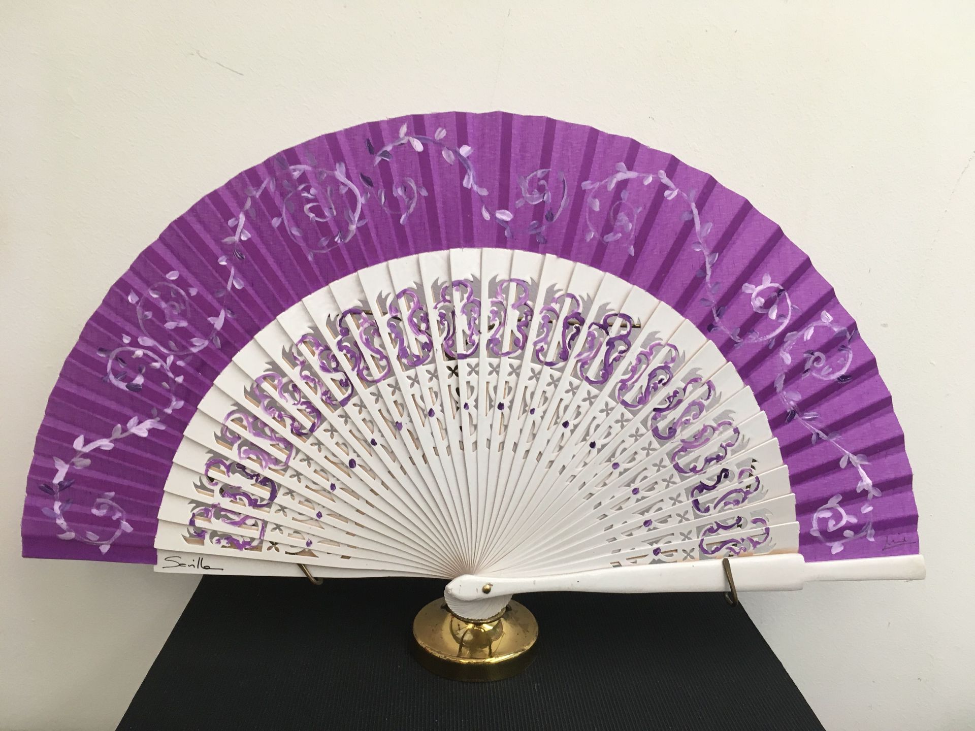 Un abanico morado y blanco está sobre una mesa.