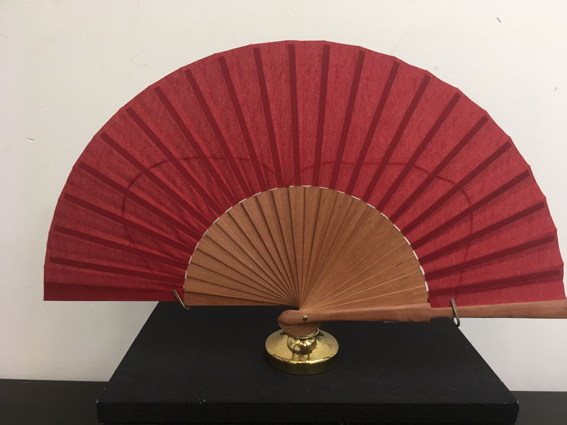 Un ventilador rojo está sentado encima de una caja negra