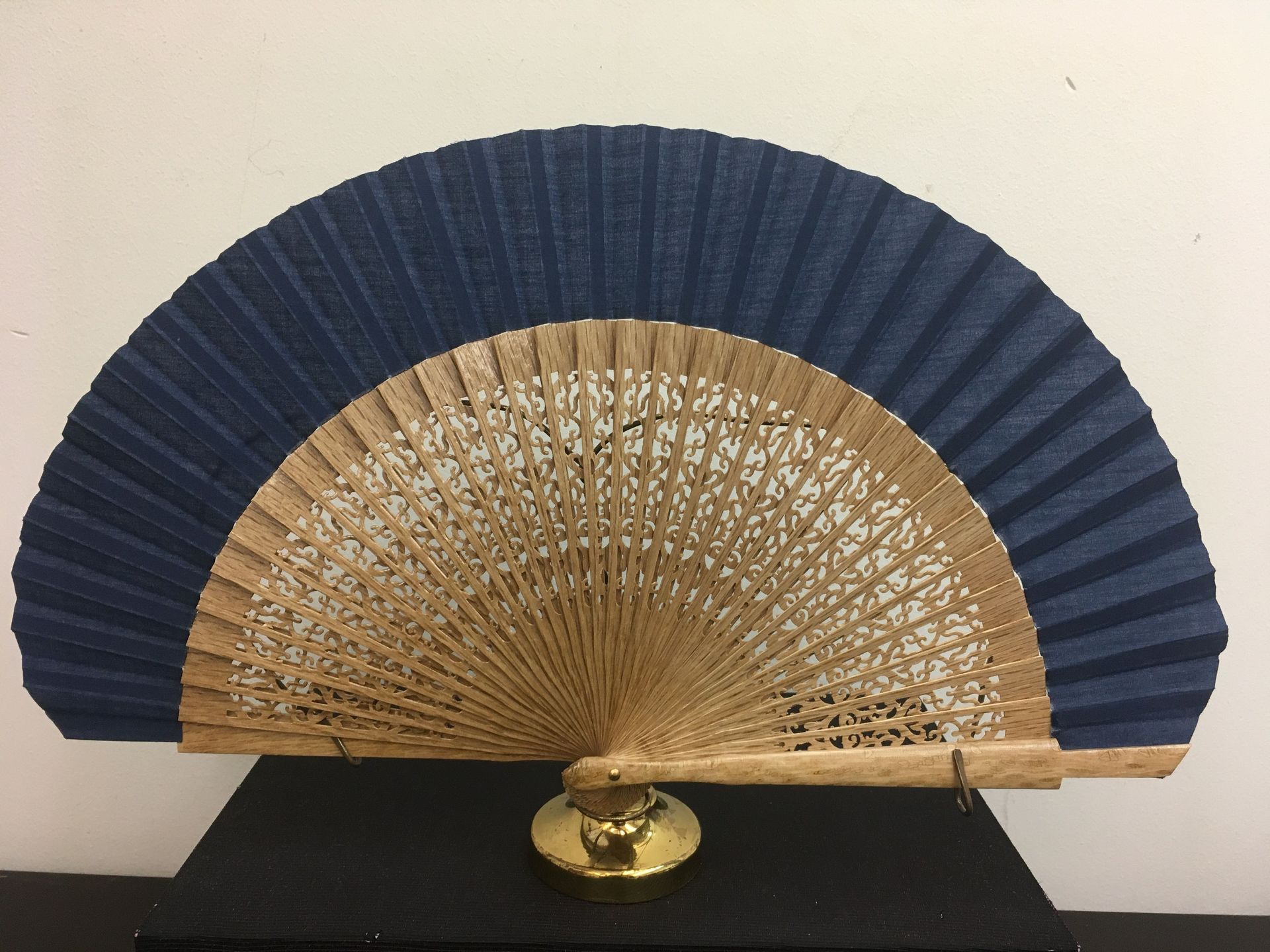 Un abanico azul y marrón está sentado encima de una mesa negra.