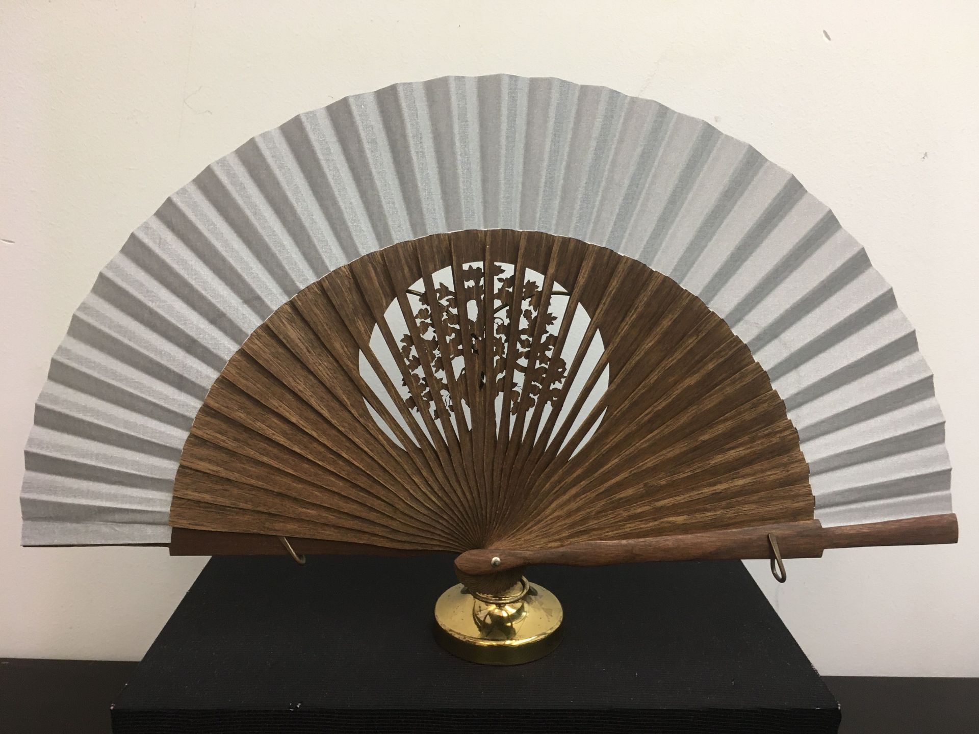 Un abanico con mango de madera está sobre una mesa.