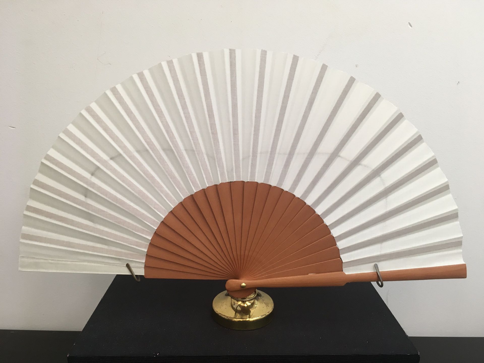 Un abanico blanco con un mango marrón está sobre una mesa.