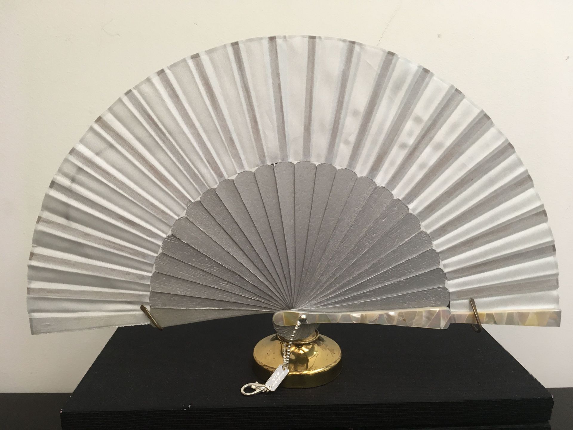 Un ventilador plateado está sentado encima de una caja negra.