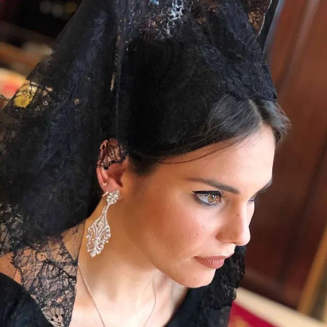 Una mujer que lleva un velo de encaje negro y pendientes.