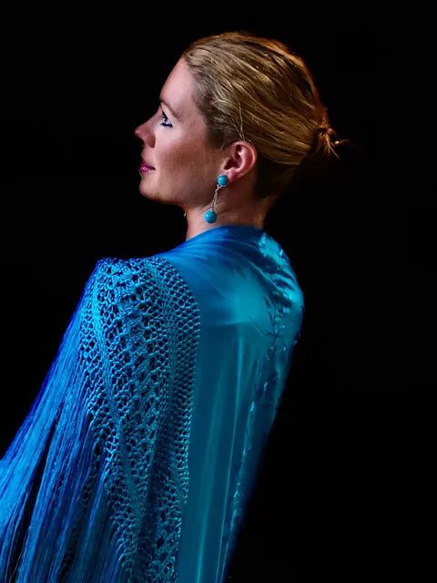 La mujer lleva un chal azul y pendientes.