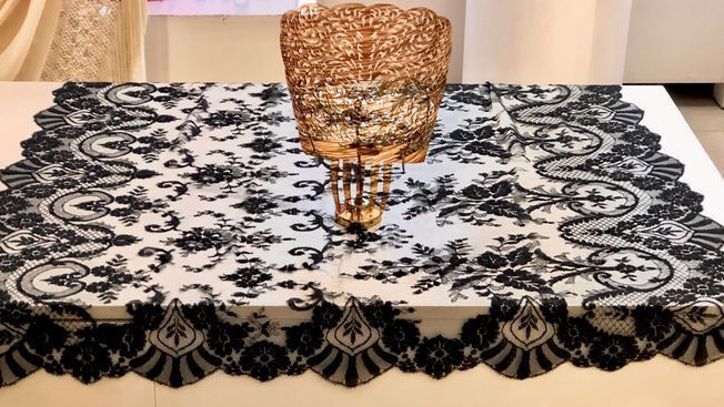 Un mantel de encaje blanco y negro con un jarrón encima.