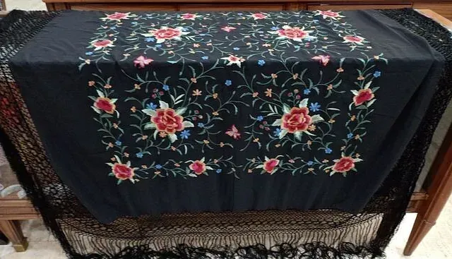 Un mantel negro con flores bordadas.