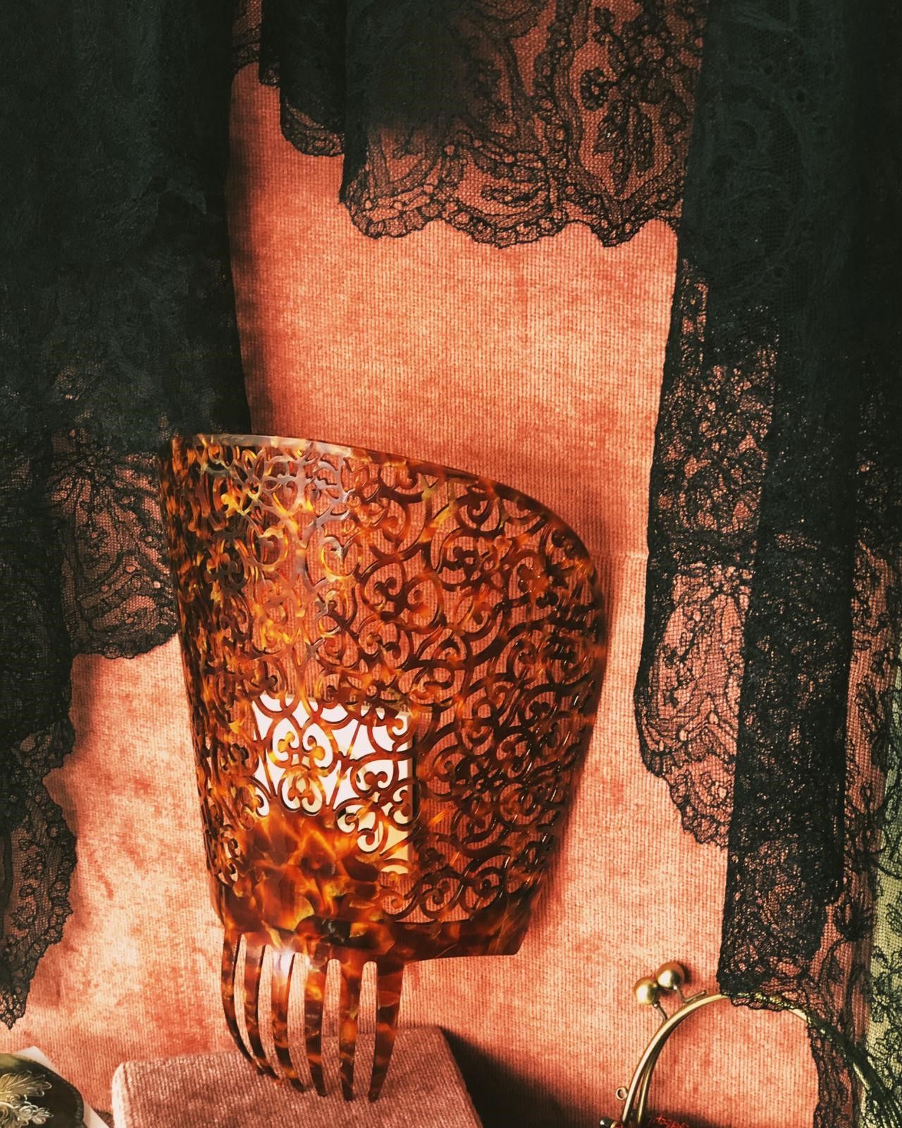 Una mujer que lleva un top de encaje negro sostiene un bolso marrón.