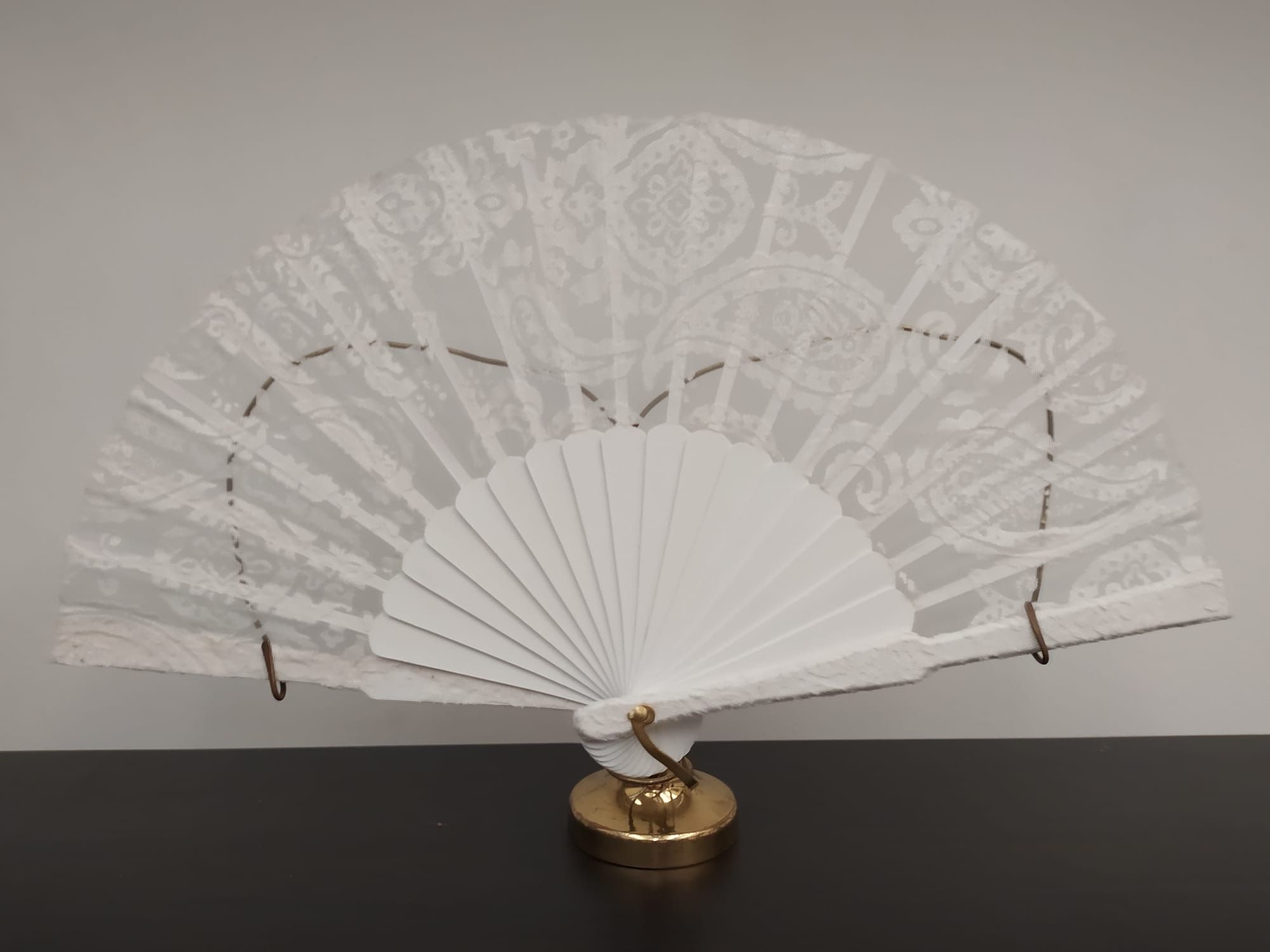 Un abanico blanco está sentado sobre una mesa negra.