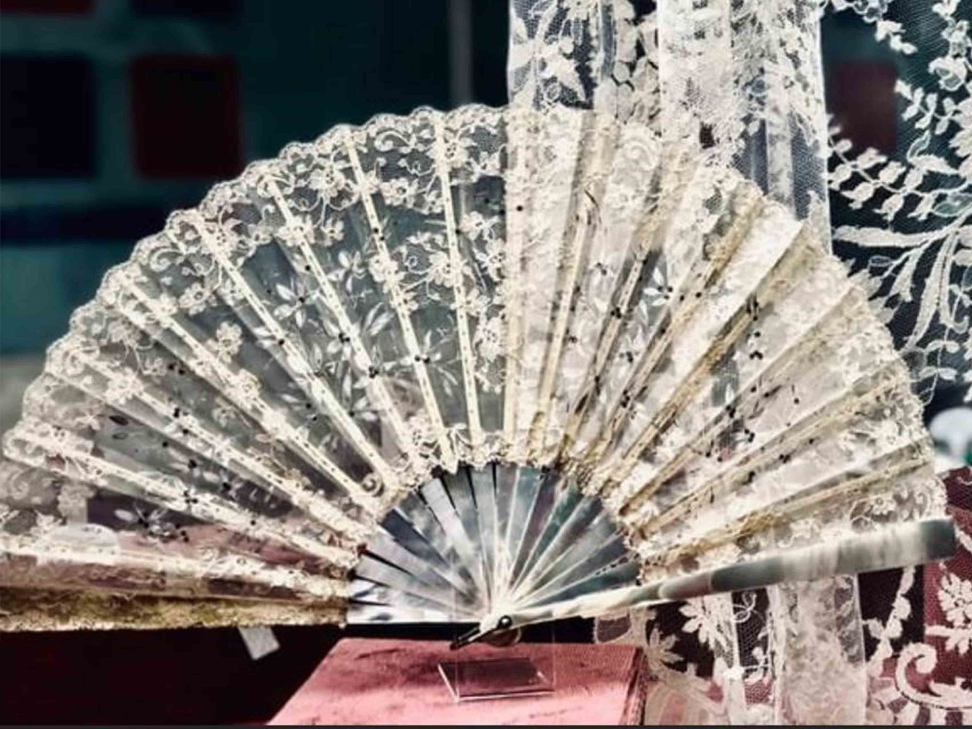Un abanico de encaje blanco está sobre una mesa.