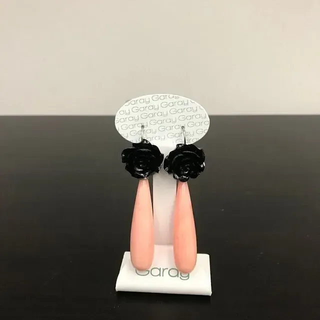 Un par de pendientes rosas con flores negras.