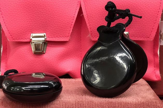 Dos castañuelas negras están sentadas al lado de un bolso rosa.