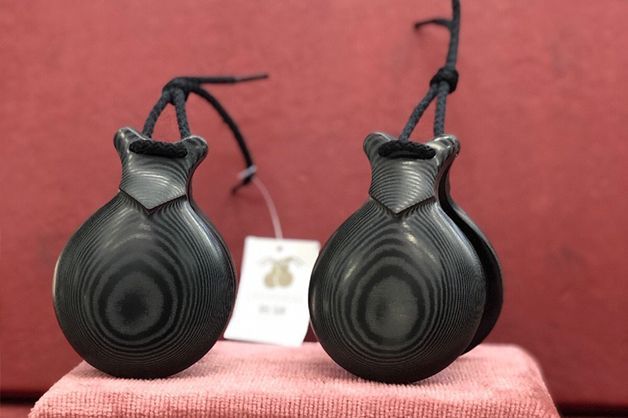 Un par de castañuelas negras están colocadas sobre un paño rojo.