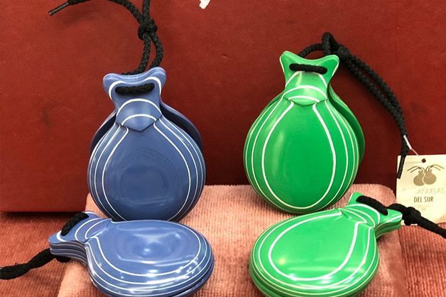 Cuatro castañuelas de diferentes colores están sobre una mesa.