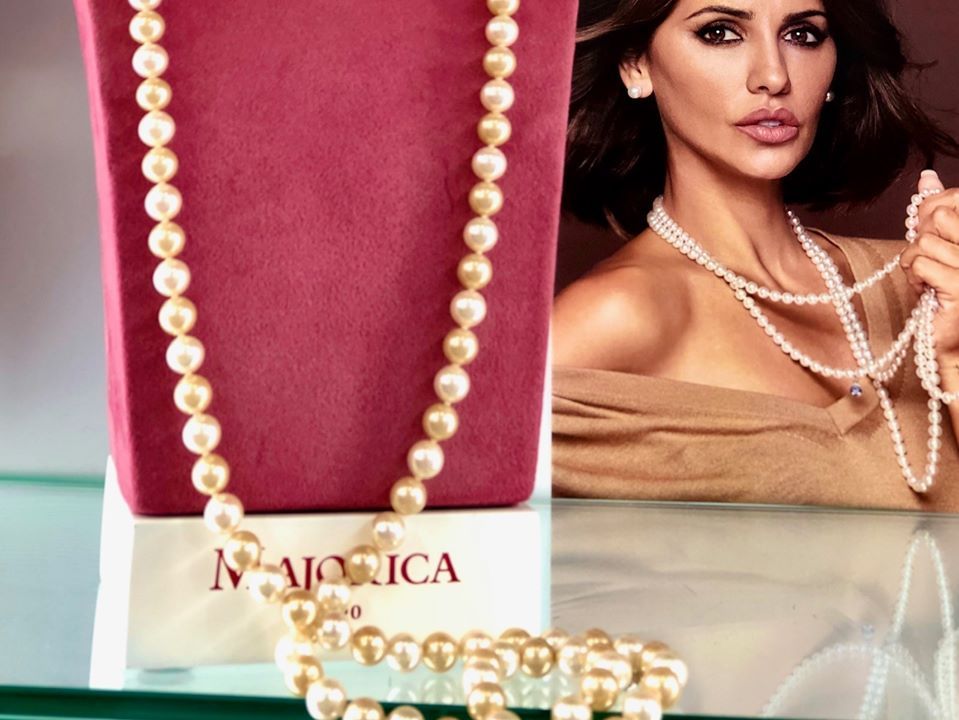 Una mujer que lleva un collar de perlas junto a una caja que dice Mónica.