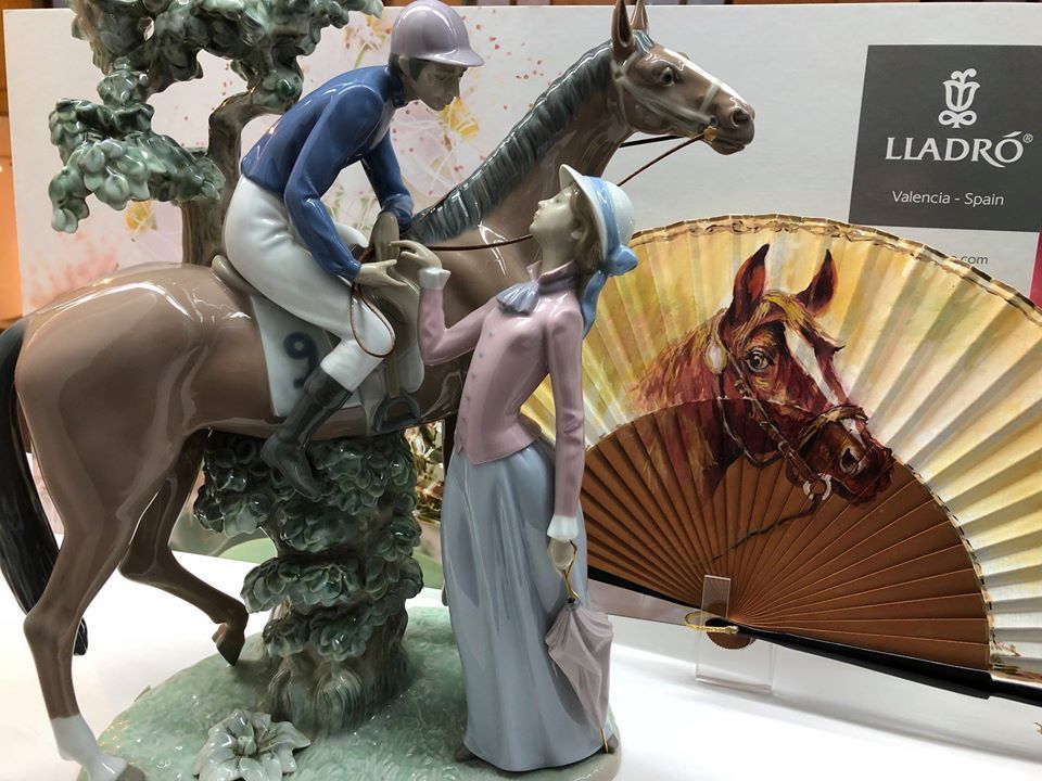 Una estatua de un hombre montado a caballo junto a una mujer parada junto a un abanico.