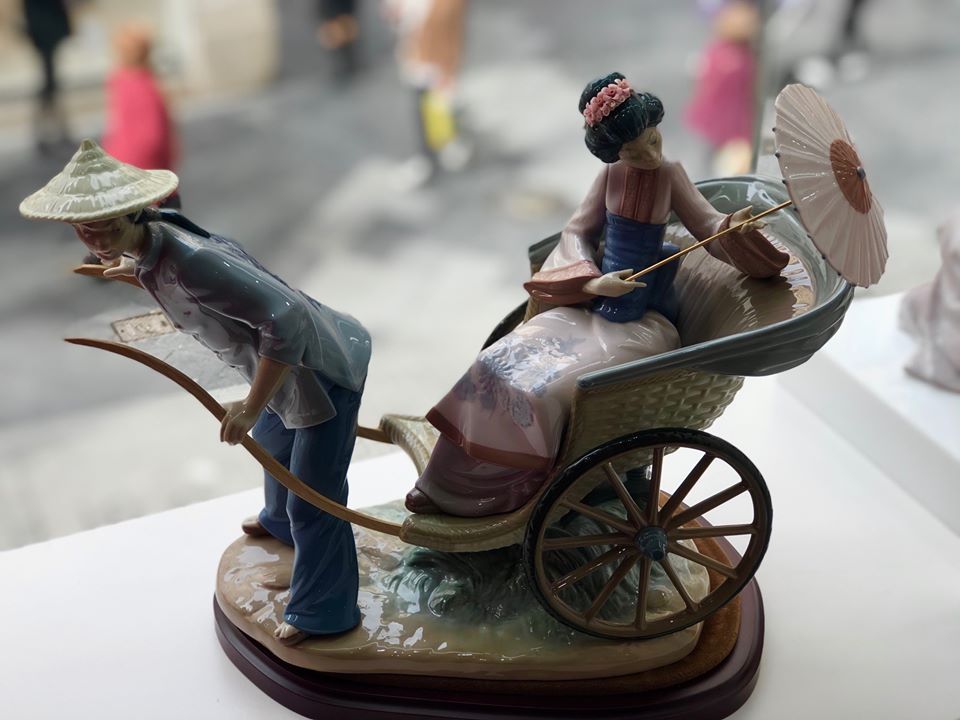 Una estatua de un hombre tirando de un carruaje con una mujer en él.