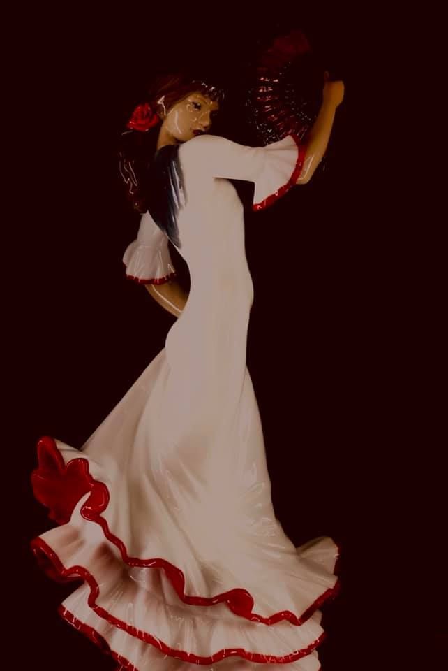 Una mujer con un vestido blanco y rojo está bailando flamenco.