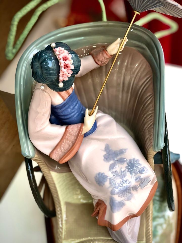 Una estatua de una mujer en un rickshaw sosteniendo un paraguas.