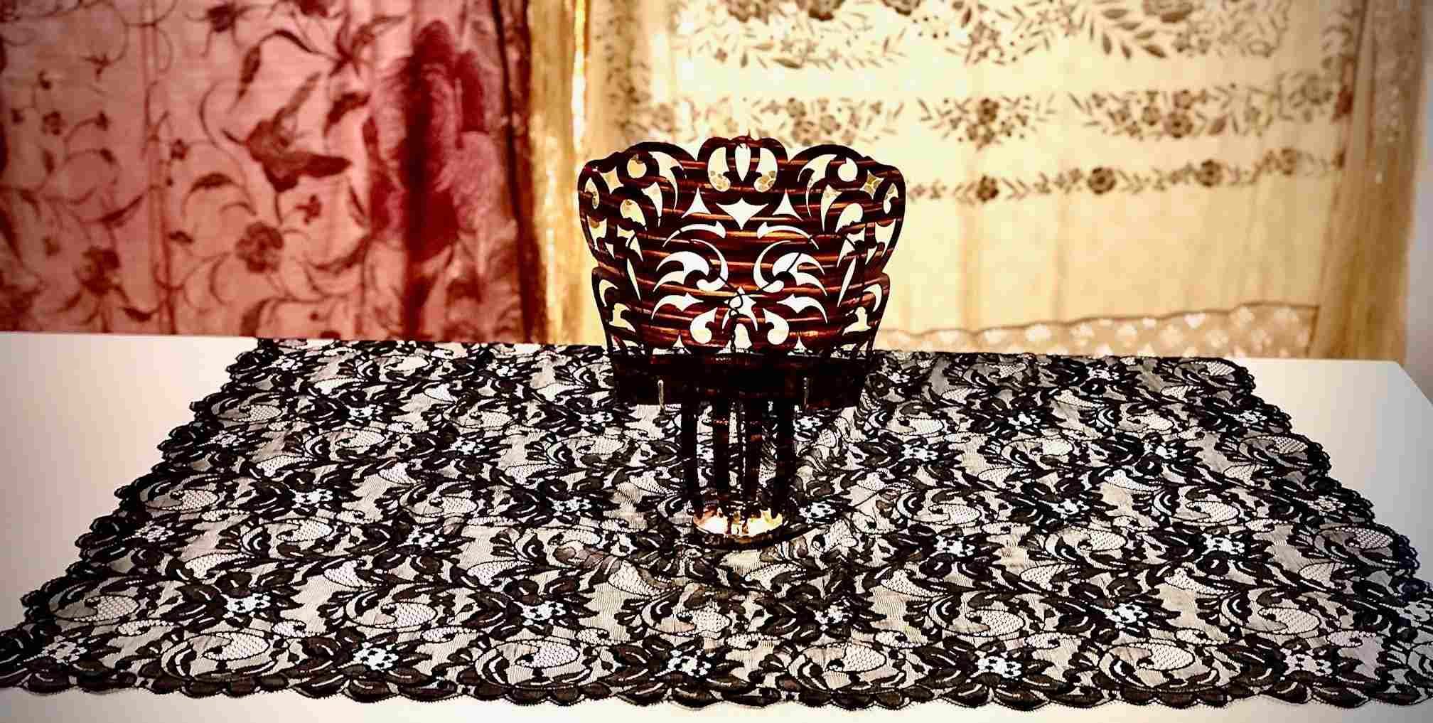 Un camino de mesa de encaje blanco y negro con un jarrón encima.