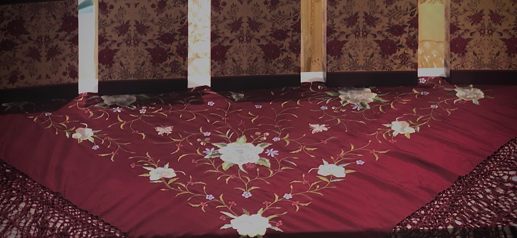 Un mantel rojo con flores blancas.