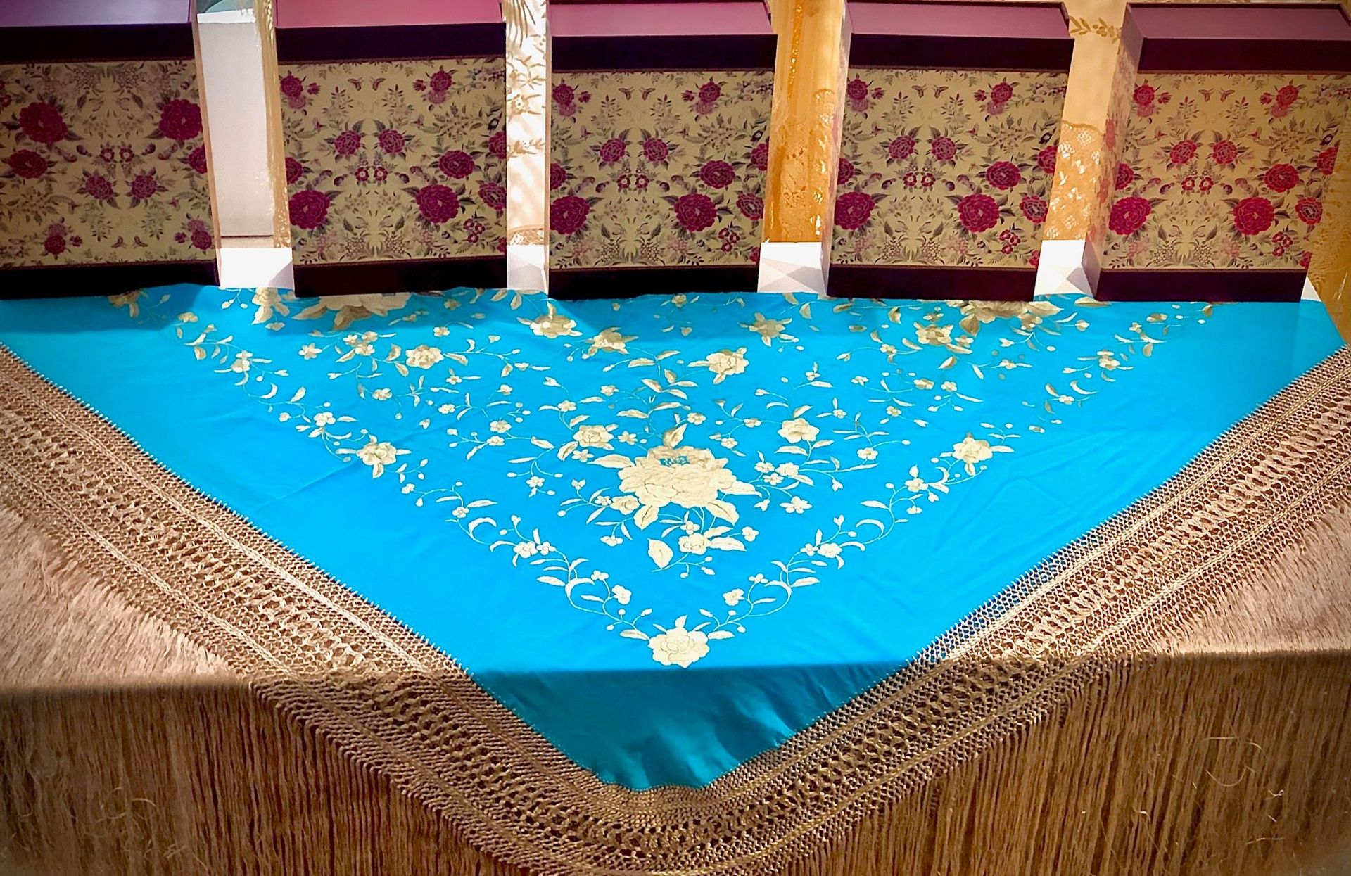Un mantel azul con bordados dorados está sobre una mesa de madera.