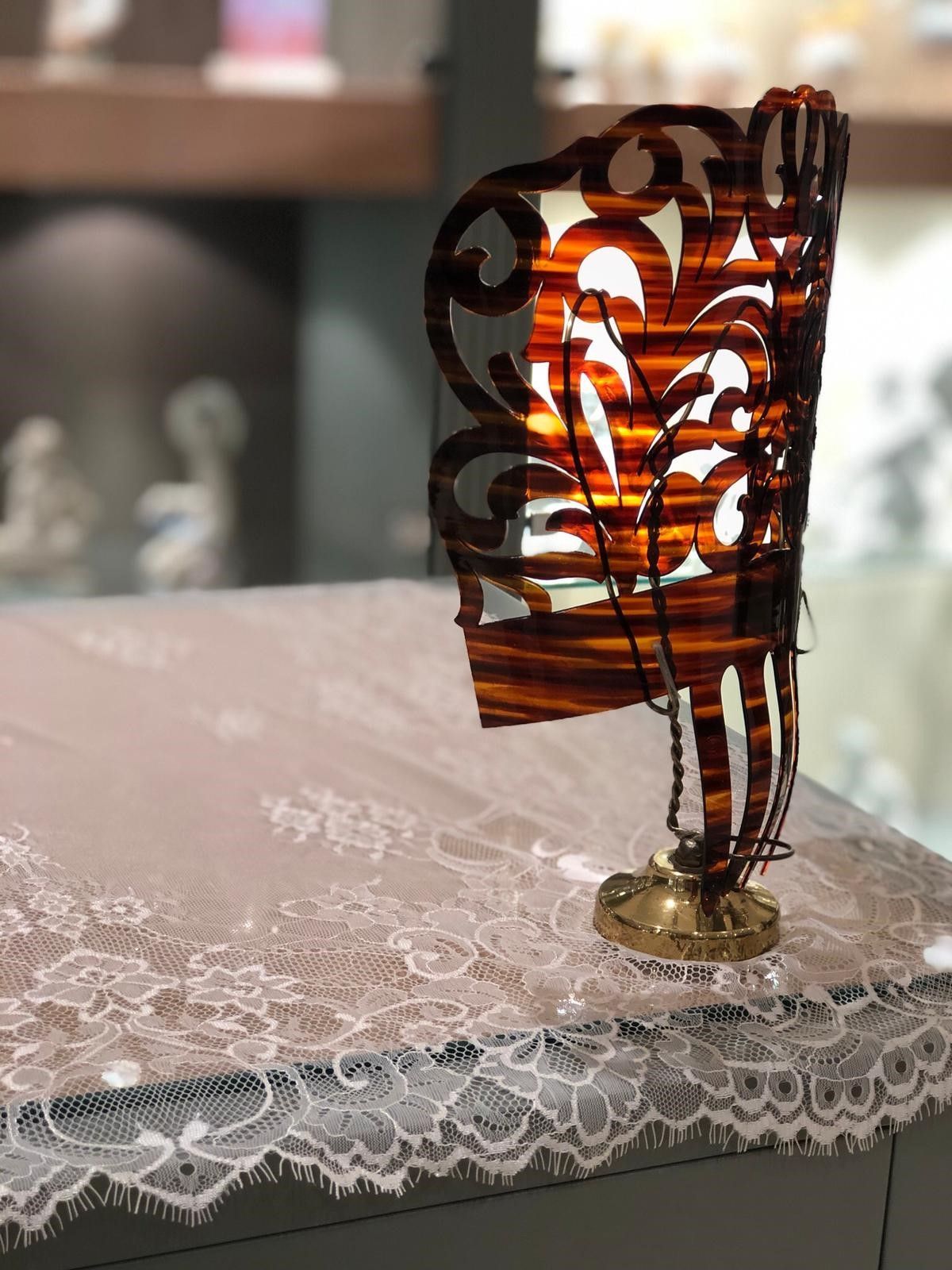 Un abanico está sentado encima de una mesa con un mantel de encaje.