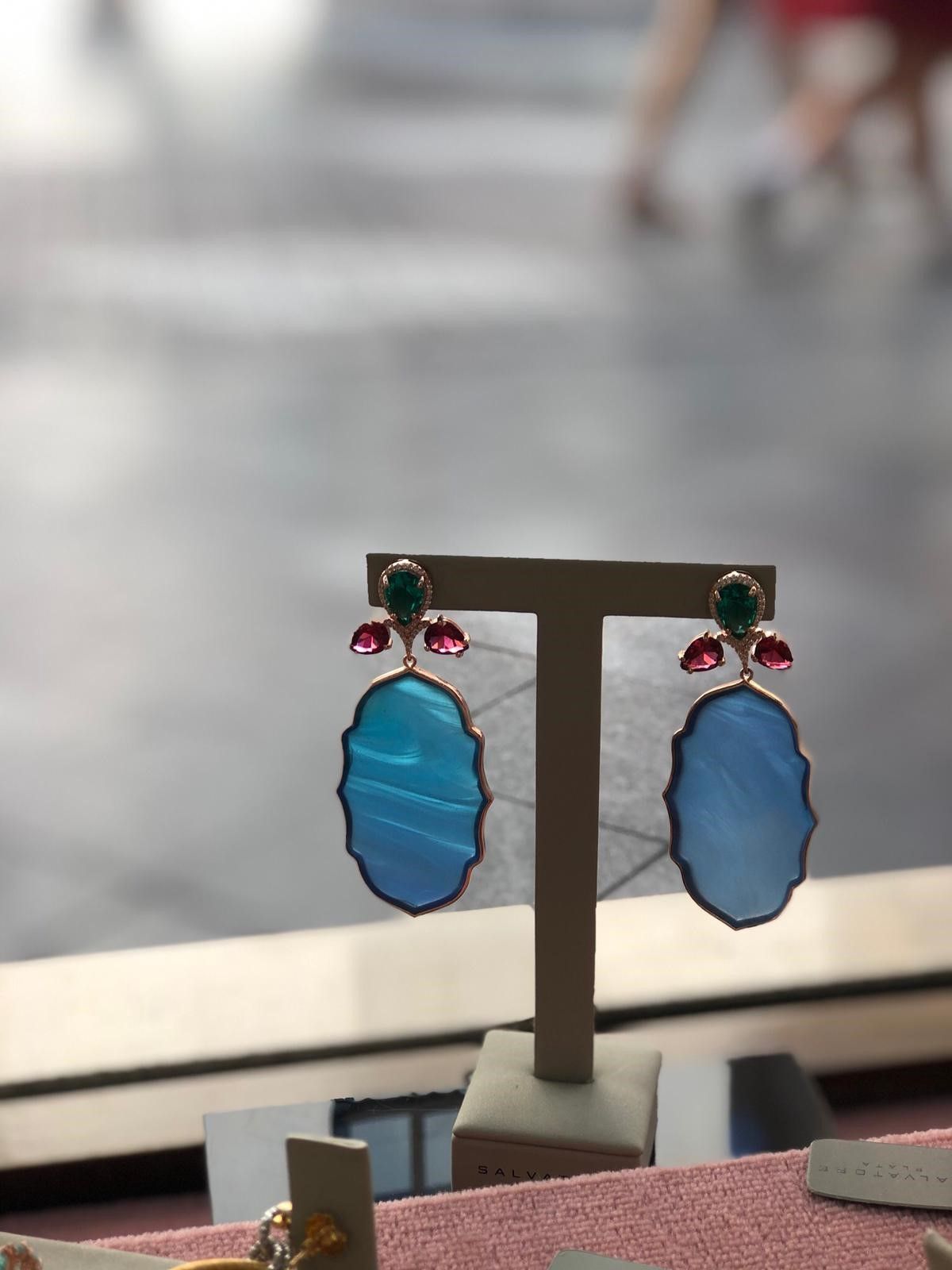 Un par de pendientes azules y verdes en exhibición.