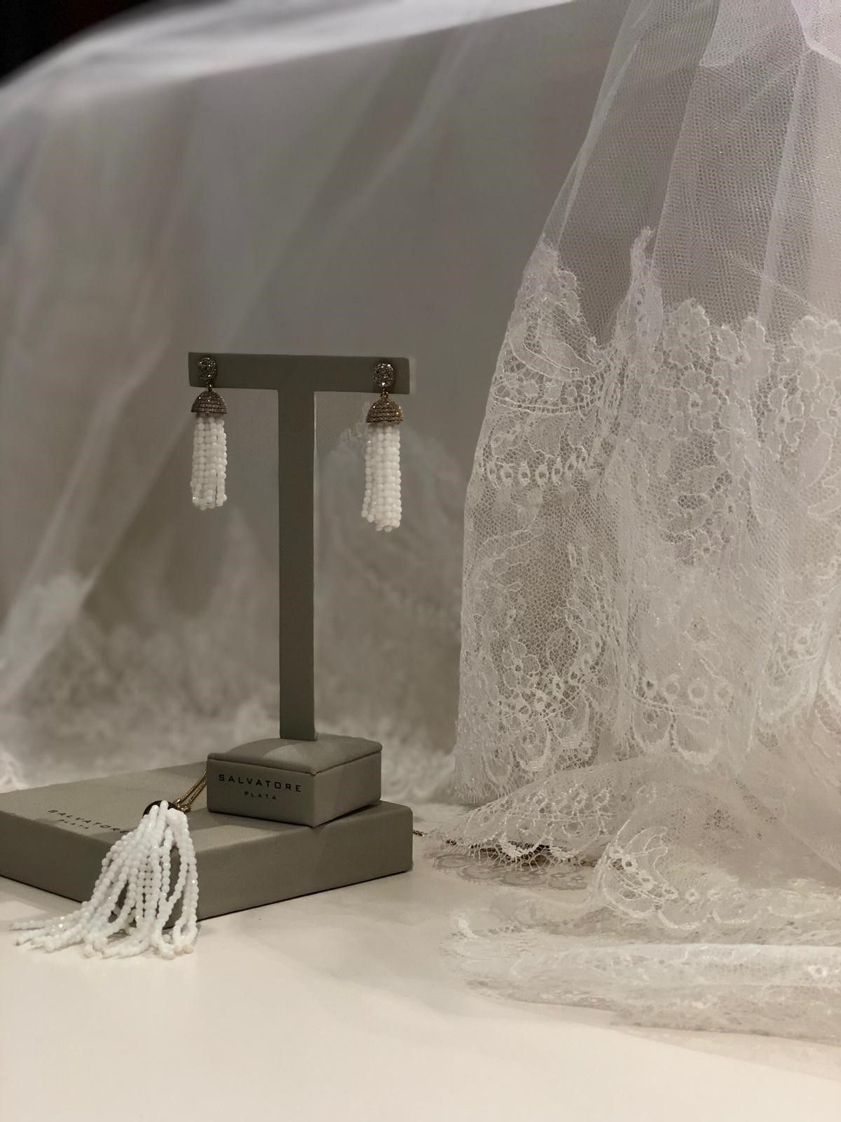 Un par de pendientes están sobre una mesa al lado de un velo.