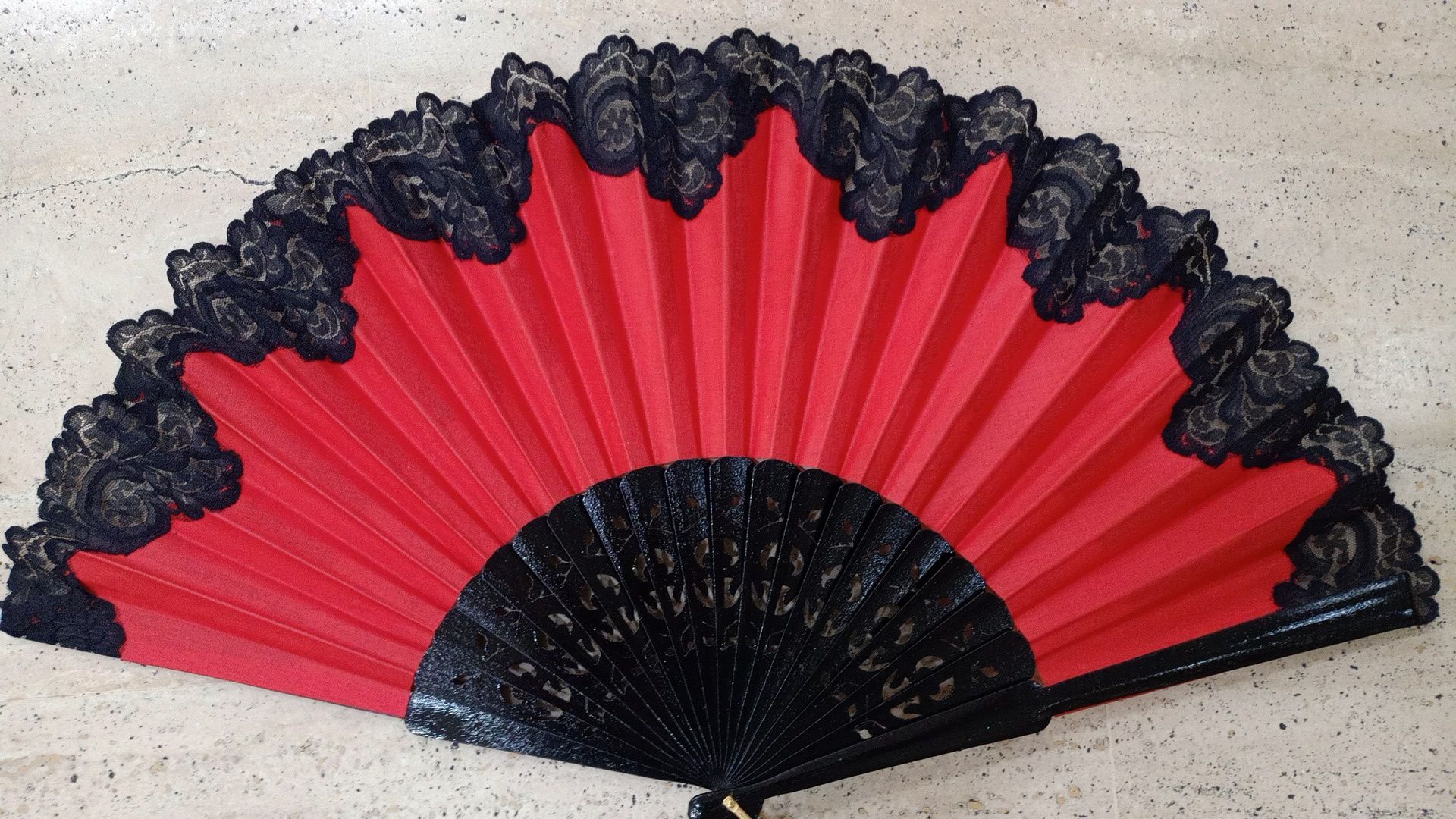 Un abanico rojo con encaje negro.
