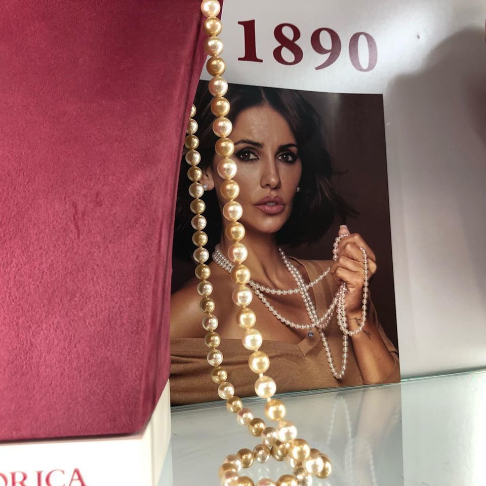 Una mujer que lleva un collar de perlas junto a un libro que dice 1890