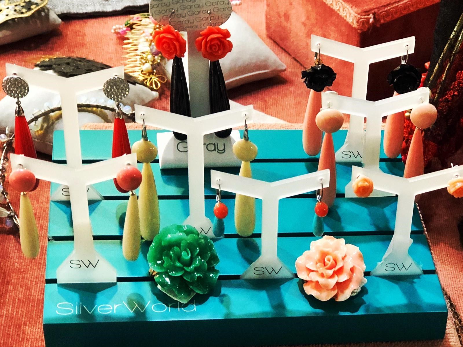 Una exhibición de aretes y una flor en una caja azul que dice mundo de plata