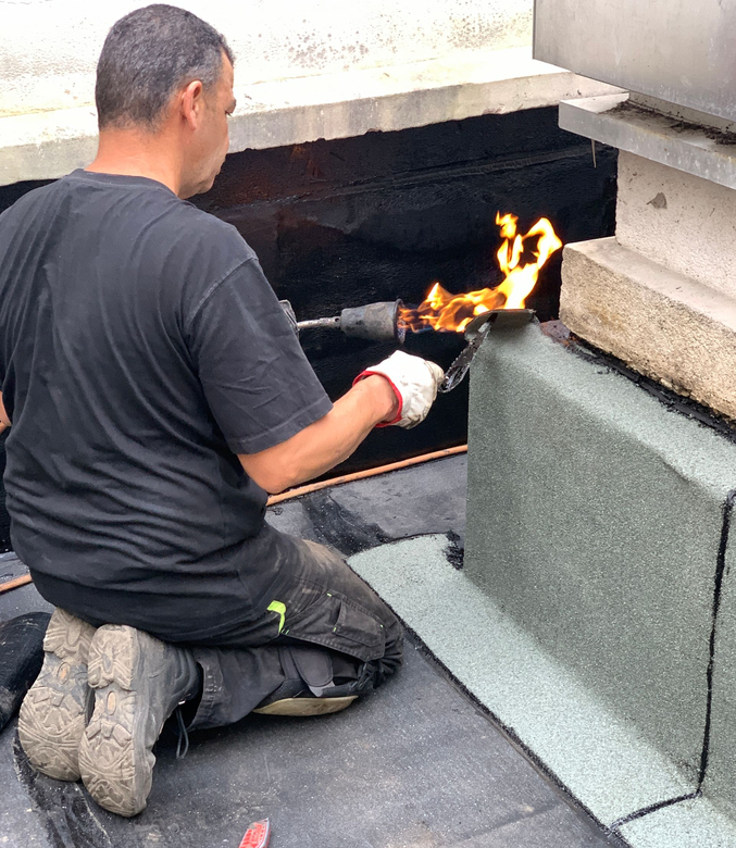 Un homme étanche votre toiture-terrasse avec un chalumeau