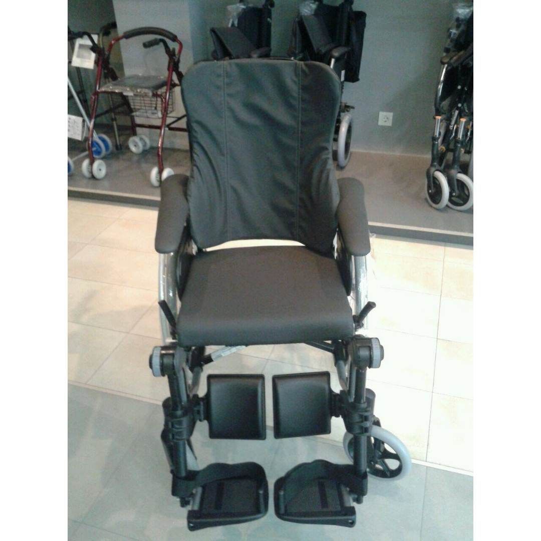 Una silla de ruedas negra está sentada sobre un piso de baldosas en una tienda.