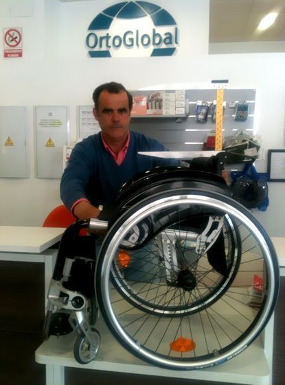 Un hombre en silla de ruedas frente a un cartel que dice ortoglobal