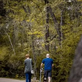 Un hombre y una mujer caminan por un sendero en el bosque.