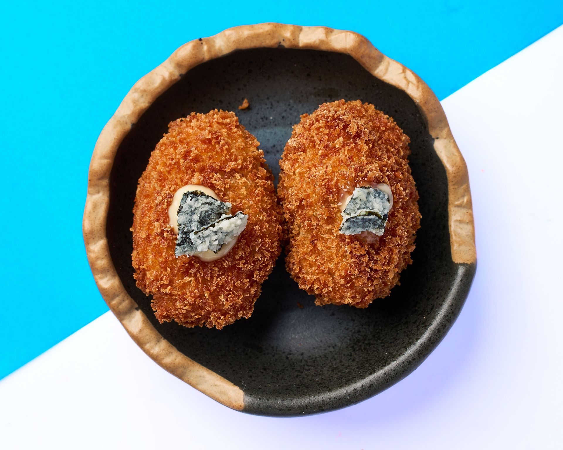 Una bandeja de madera llena de arroz y camarones sobre una mesa.