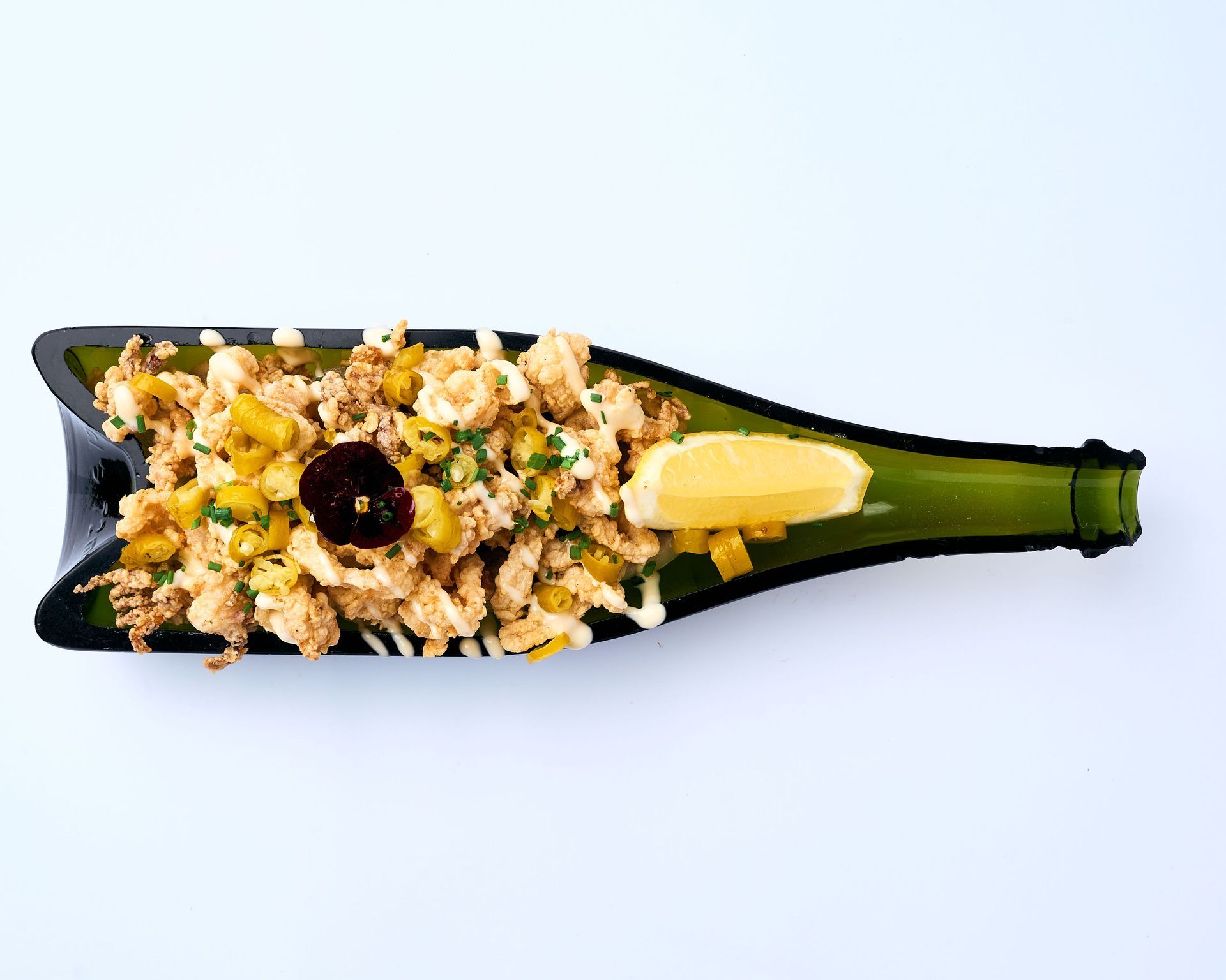 Un plato negro cubierto con calamares fritos y aceitunas.