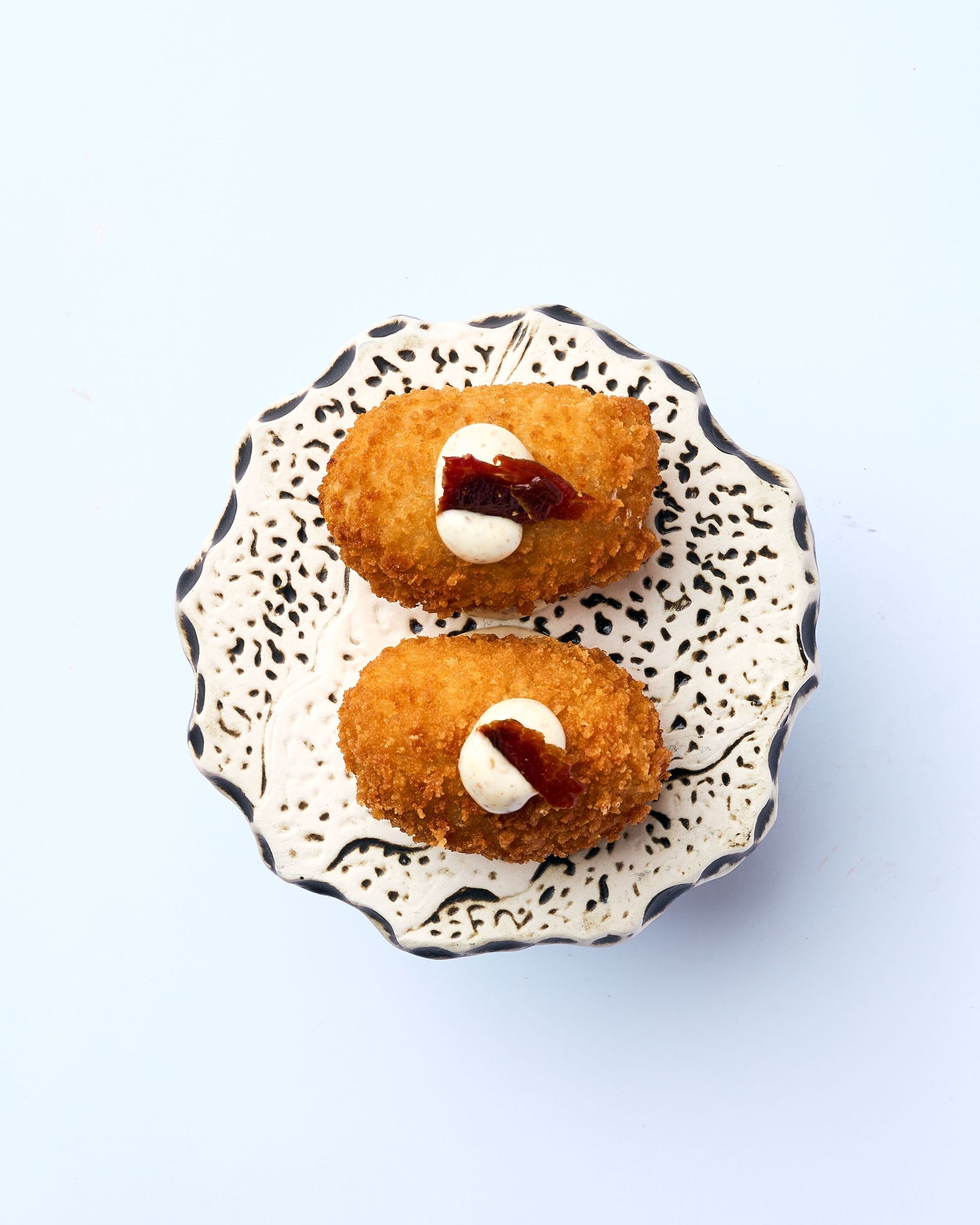 Un plato blanco cubierto con aperitivos y una cuchara sobre un fondo negro.