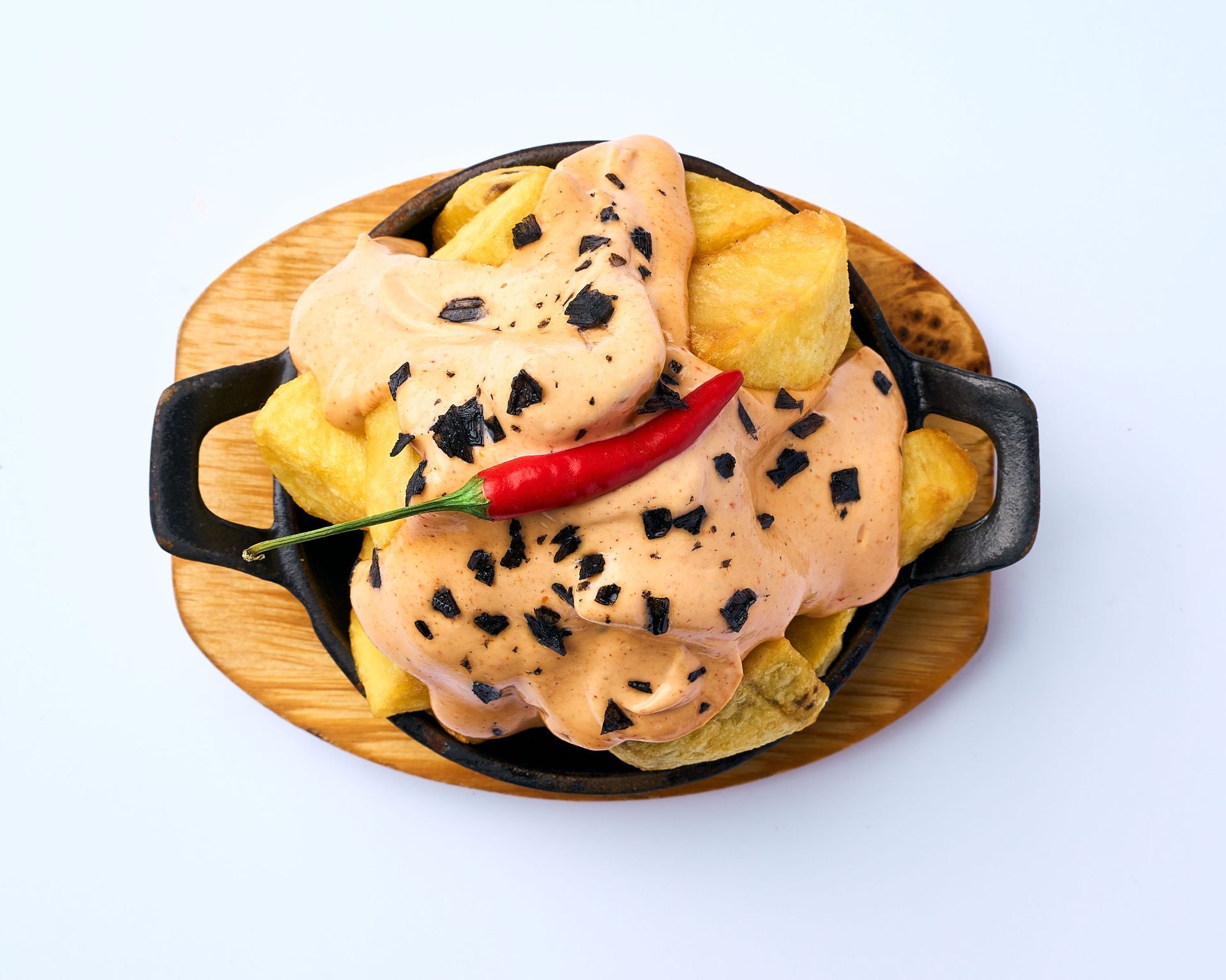 Un bol de patatas con salsa y un pimiento rojo encima.