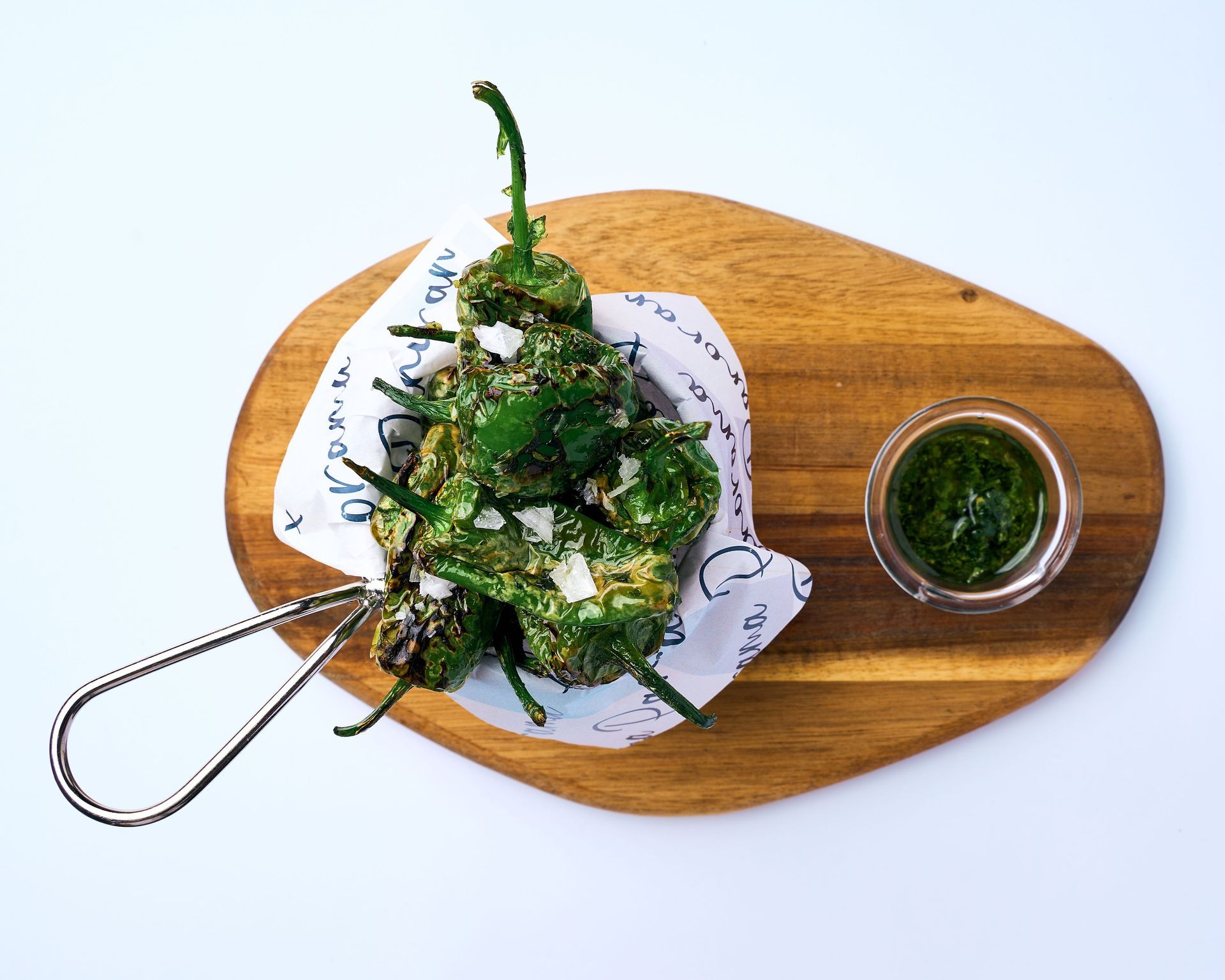 Un bol de pimientos envueltos en papel de periódico sobre una tabla de cortar de madera.