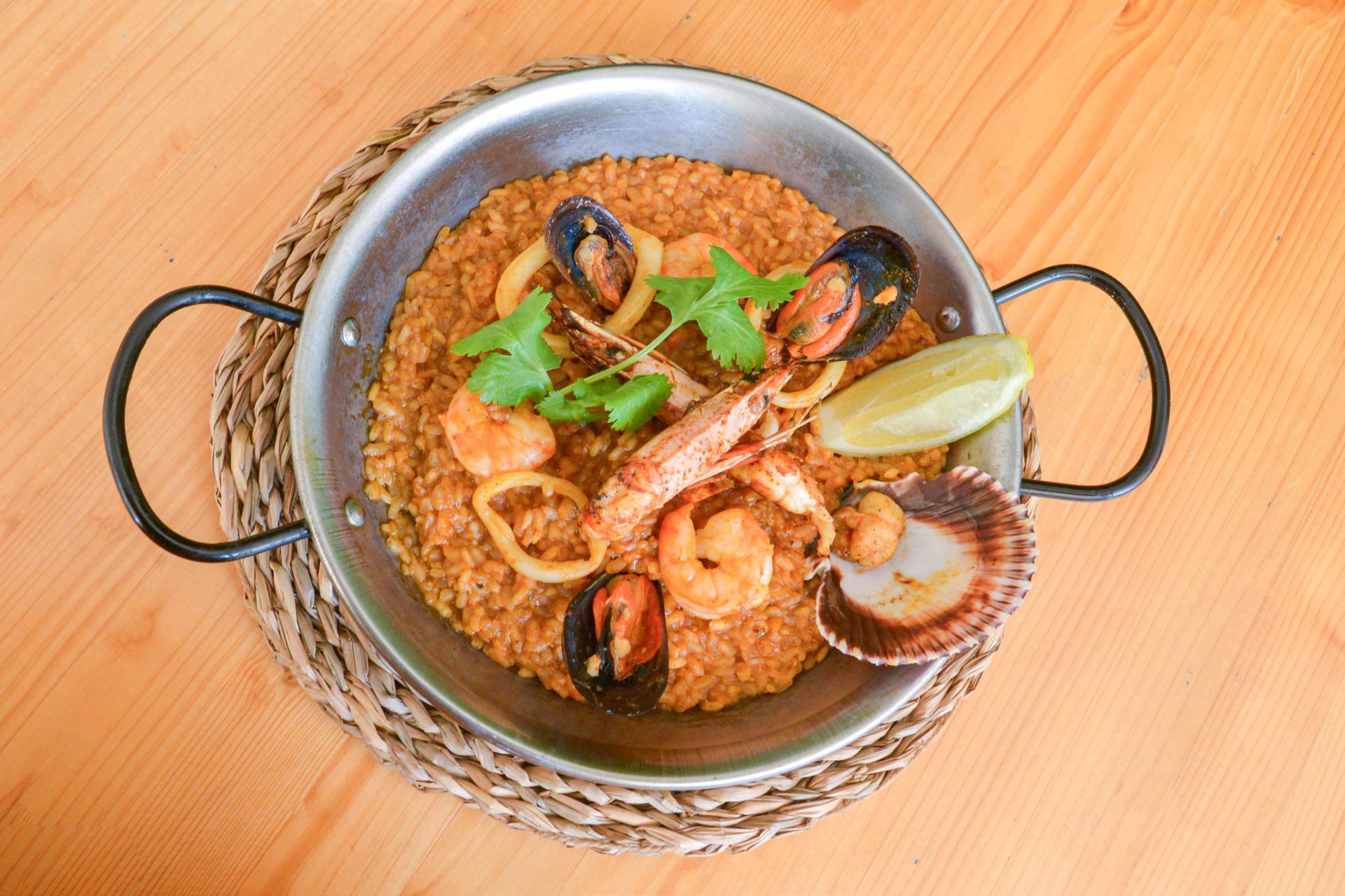 Una bandeja de madera llena de arroz y camarones sobre una mesa.