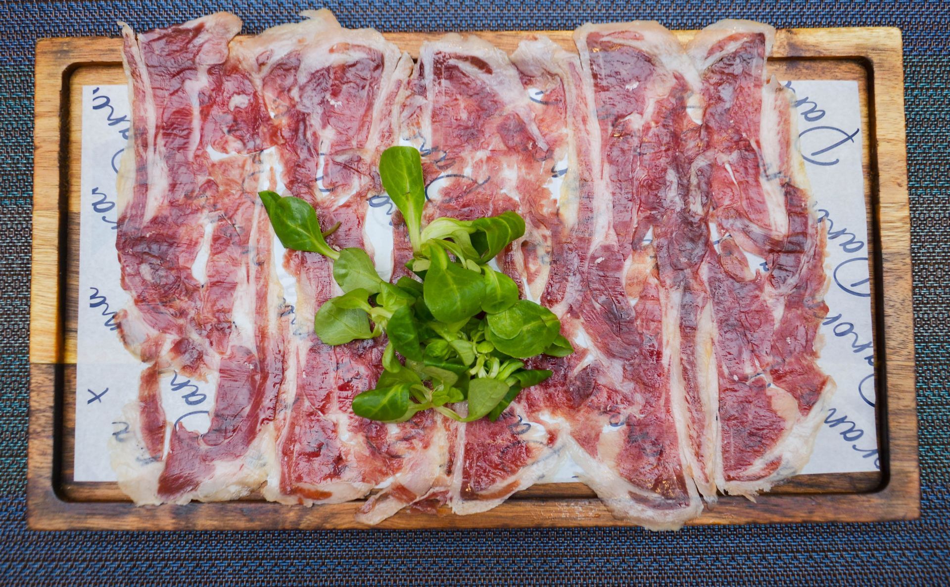 Una tabla de cortar de madera cubierta con carne y verduras.