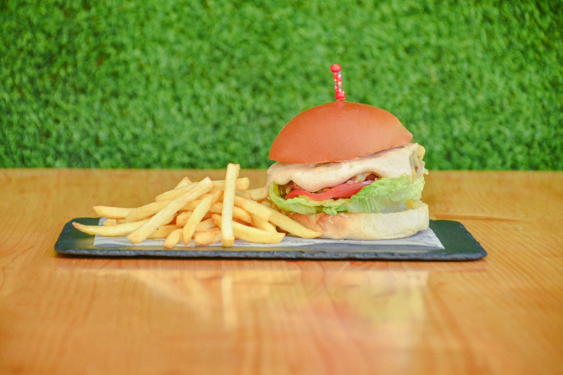 Una hamburguesa y papas fritas están sobre un periódico sobre una tabla de cortar.