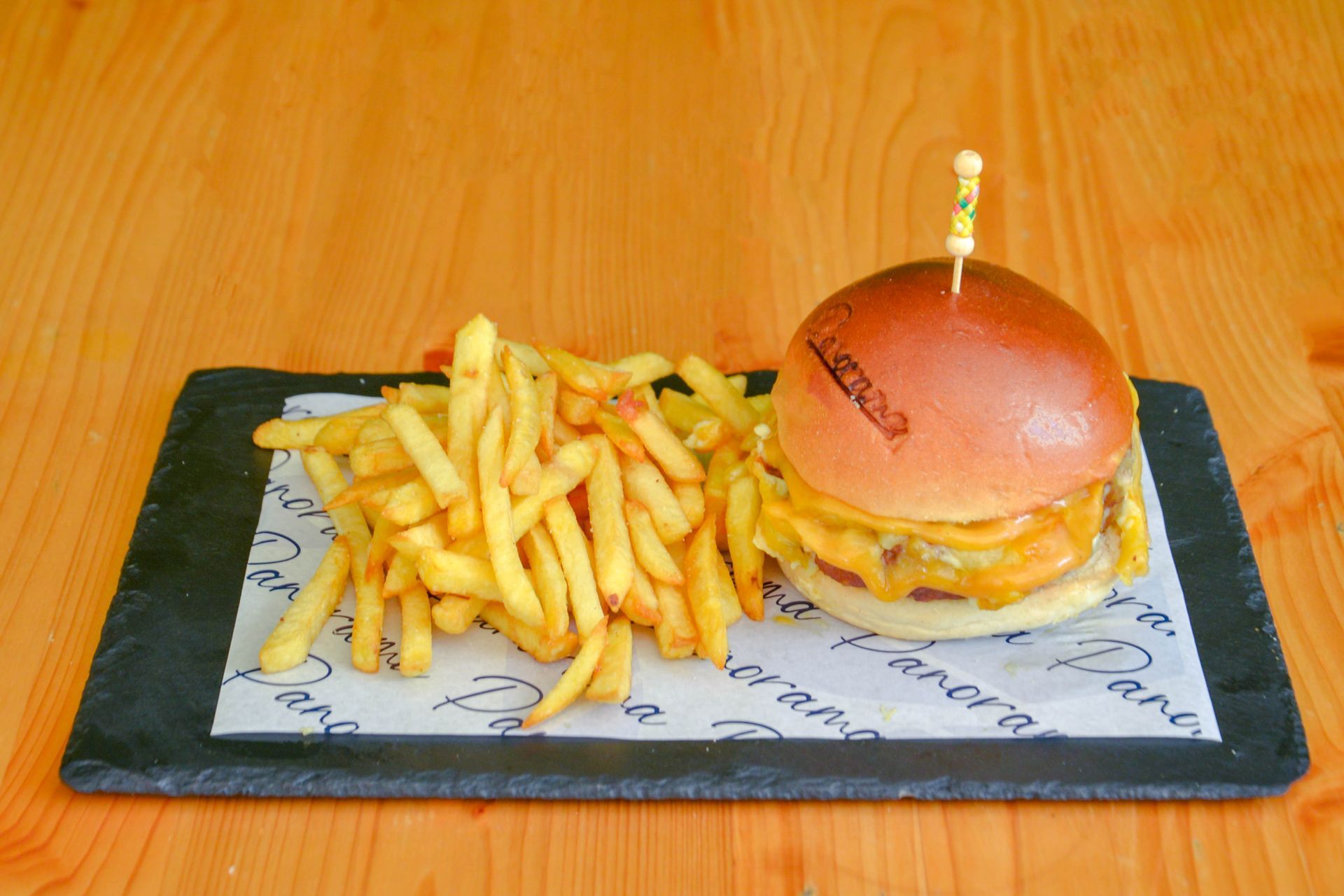 Una hamburguesa y papas fritas en una tabla de cortar sobre una mesa.