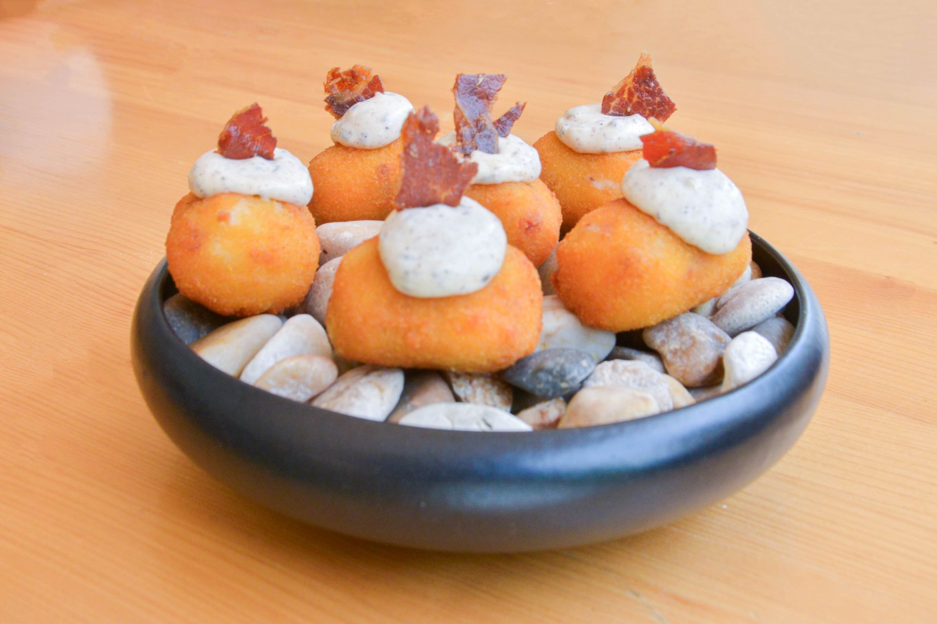 Un plato blanco cubierto con aperitivos y una cuchara sobre un fondo negro.