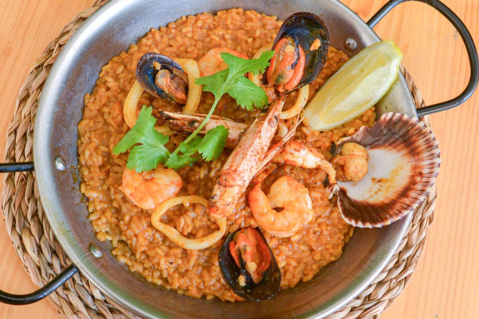 Una bandeja de madera llena de arroz y camarones sobre una mesa.