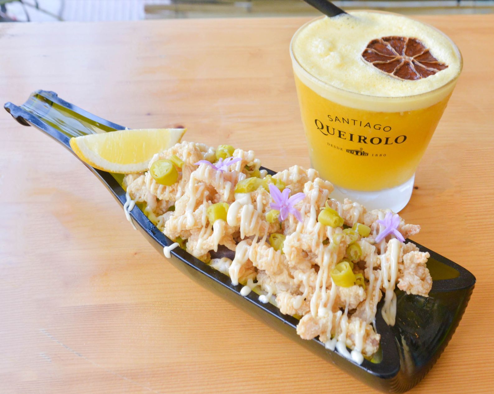 Un plato negro cubierto con calamares fritos y aceitunas.